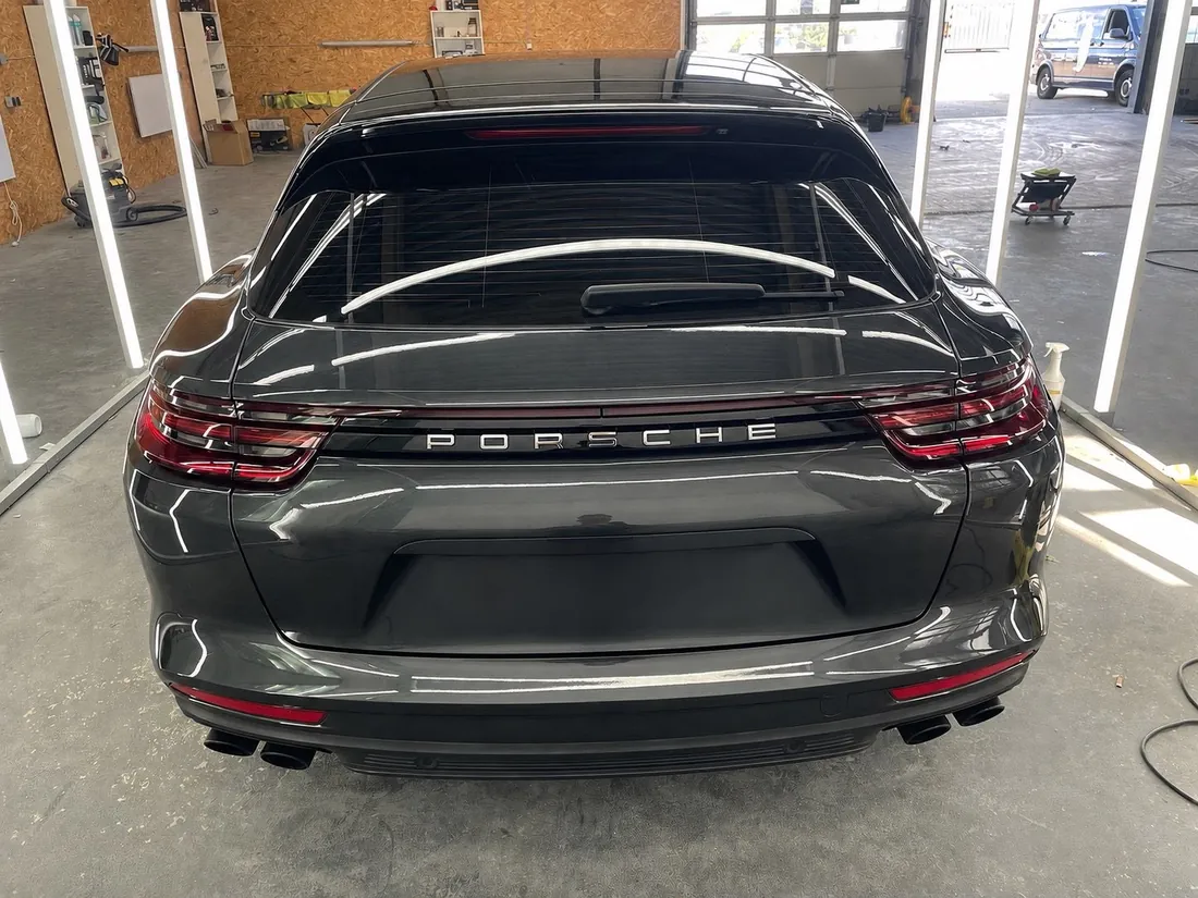 Porsche Panamera von hinten mit tiefem Hochglanzlack in der beleuchteten Aufbereitungs-Lichtbox